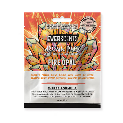 Everscents Aroma Pack under-seat car air freshener pouch. The upper half features a multi-colored orange crystal cluster design over a glowing yellow scribbled background with the brand text 'Everscents Aroma Pack' and the ‘FIRE OPAL’ scent name, while the lower white half displays a text description of the scent profile and product information, shown isolated on a white background.