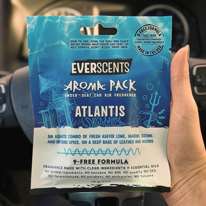 Everscents Aroma Pack in the scent Atlantis held in front of a black car dashboard. The pouch is large, covering the hand holding it.