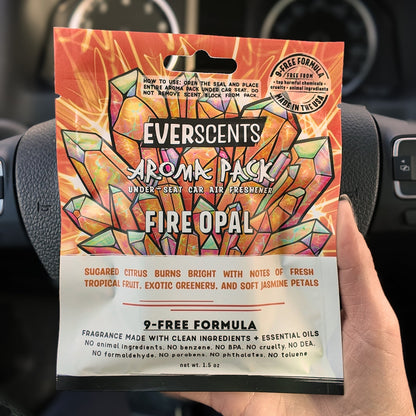 Everscents Aroma Pack in the scent Fire Opal held in front of a black car dashboard. The pouch is large, able to cover the hand holding it.